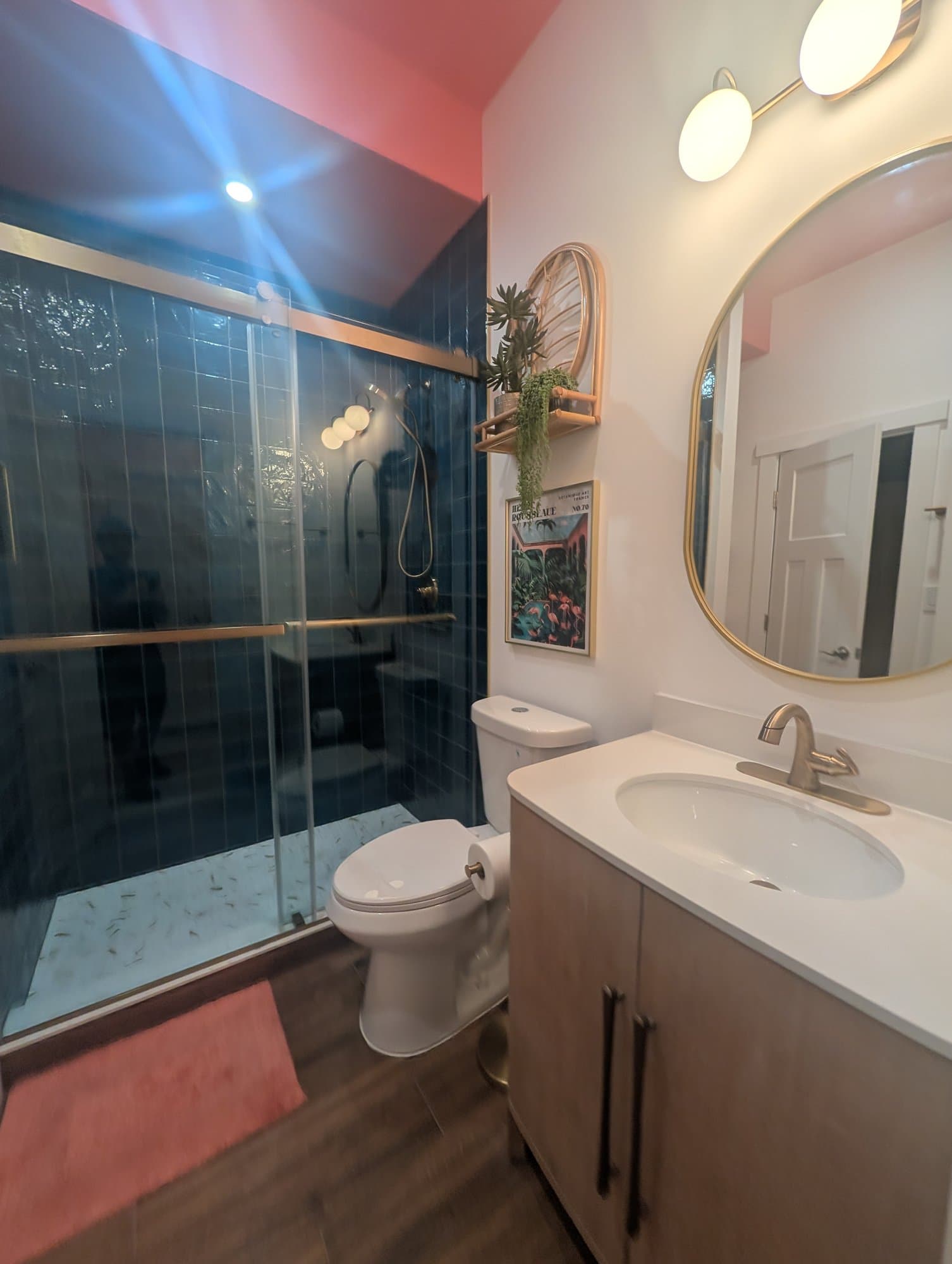 Finished basement bathroom vanity with a round mirror and gold fixtures