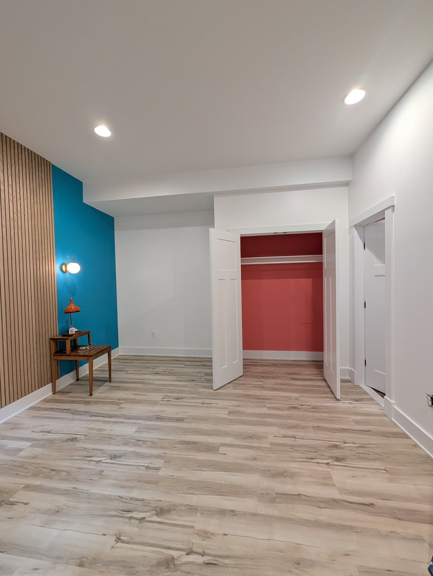 Finished basement room with a coral-painted closet interior and new flooring